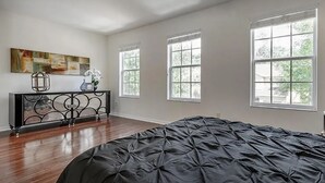 A bedroom with a large bed, a desk with a lamp, and three windows. - Charming 2-bedroom townhome in beautiful Riverview with WiFi, AC (Riverview)