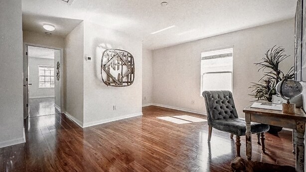 A spacious room with hardwood flooring, a large abstract artwork on the wall, a plush armchair, and a desk with a vintage clock. - Charming 2-bedroom townhome in beautiful Riverview with WiFi, AC (Riverview)