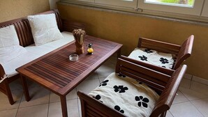 A room with a wooden table and chairs, a sofa, and a window with blinds.