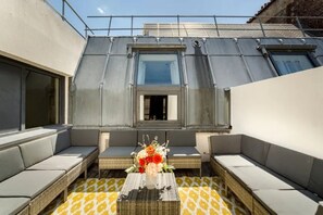 Un espacio de estar al aire libre con una mesa, cojines y un arreglo floral.