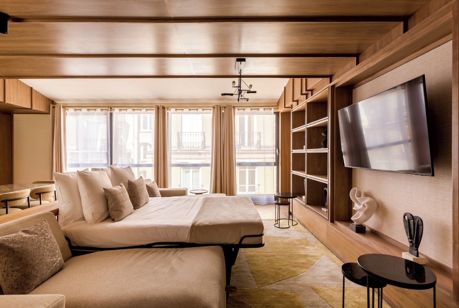 Habitación de hotel moderna con una cama grande, un sofá, un televisor y vistas a la ciudad.