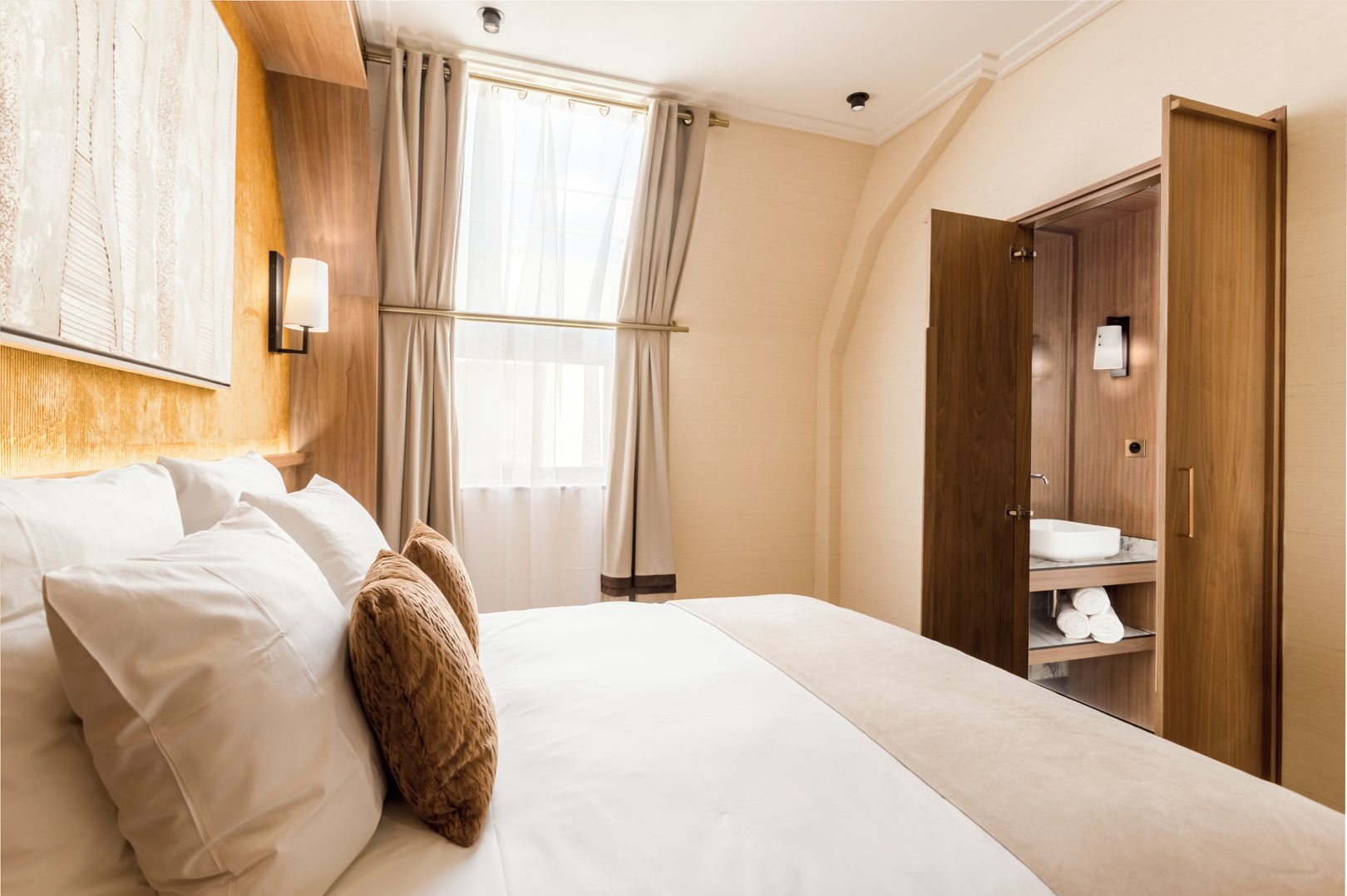 A hotel room with a large bed, a wooden headboard, a vanity with a mirror, and a wardrobe.