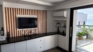 A modern kitchen with a flat-screen TV, white cabinets, and a black countertop. - Flat Frente Mar com Terraço, perto Gran Marquise hotel  e praia (Meireles Fortaleza)