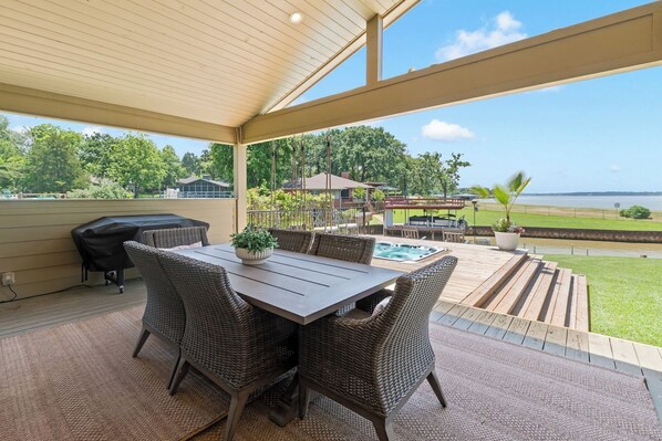 Une terrasse extérieure avec une table et des chaises, un jacuzzi et une vue sur un plan d’eau.