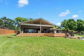 A modern house with a covered patio, a fenced backyard, and a well-maintained lawn.