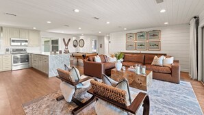 A spacious living area with a pool table, leather sofas, and a marble kitchen.