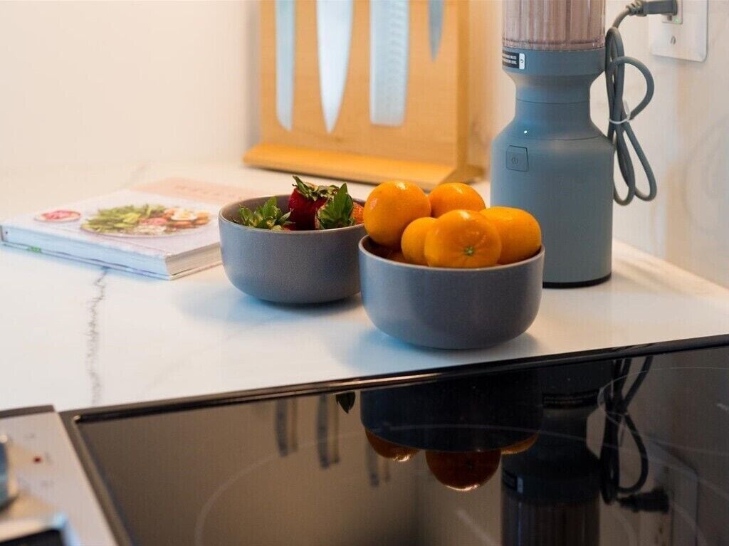 A kitchen counter with a bowl of fruit, a book, and a coffee maker.