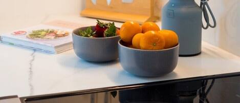 A kitchen counter with a bowl of fruit, a book, and a coffee maker.