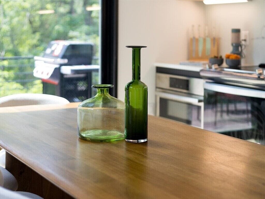 A wooden table with two green glass bottles.
