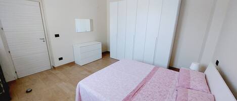 A bedroom with a bed, a wardrobe, a dresser, and a door.