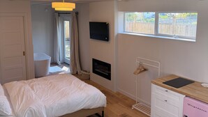 Ein Schlafzimmer mit einem Bett, einem kleinen Schreibtisch, einem rosa Schrank, einem Kamin und einem Fenster mit Blick nach draußen.