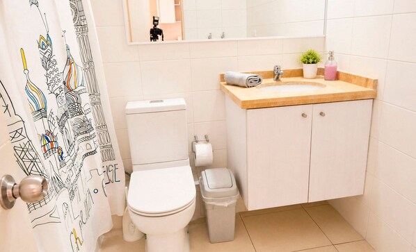 Une salle de bain avec des toilettes, un lavabo et une poubelle.
