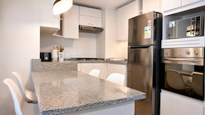 Una cucina moderna con ripiani in granito, elettrodomestici in acciaio inossidabile, mobili bianchi e forno integrato.