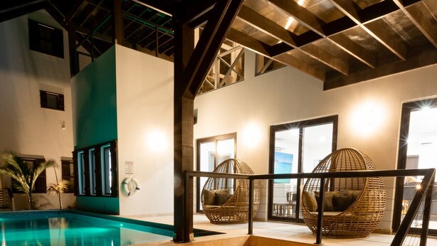 Ein moderner Außenlounge-Bereich mit Feuerstelle, Sitzgelegenheiten und einem Pool.