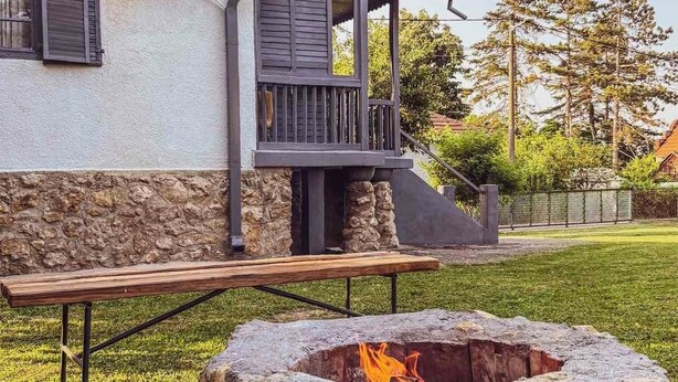 Una casa con un muro de piedra, un hogar y una terraza de madera.