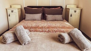 Una cama con una colcha estampada, dos almohadas, dos mesitas de noche y dos espejos en la pared.