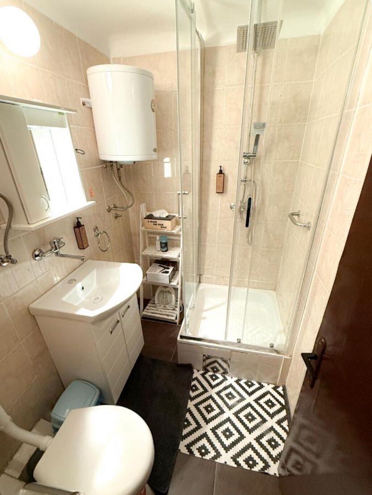 A bathroom with a shower, toilet, sink, and a mirror.