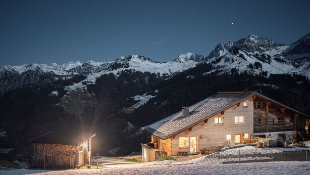 A log cabin with a stone annex, surrounded by snow-covered mountains and a starry night sky. - Vacation apartment for families and friends with many possibilities. (Fontanella)