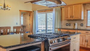 A modern kitchen with a central island, stainless steel appliances, wooden cabinets, and pendant lighting. - Near Yellowstone Lucky Dog Ranch, 3BR, Sleeps 8, Full Kitchen, Right off the Hwy (Dubois)