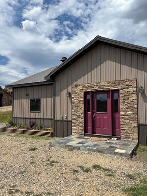 A single-story building with a stone facade and a red door.