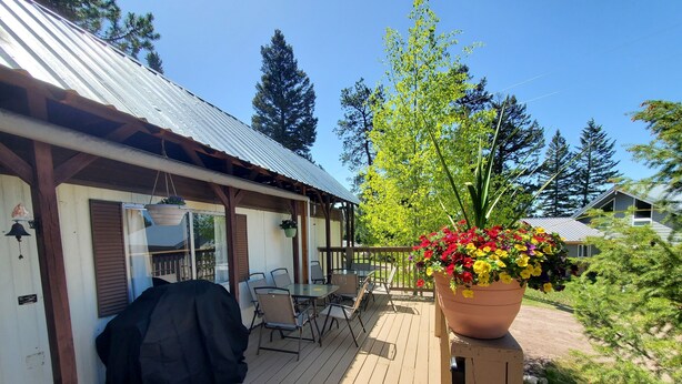 A wooden deck with outdoor furniture, a barbecue grill, and a large flower pot.