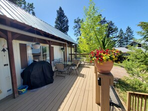 A wooden deck with outdoor furniture, a barbecue grill, and a large flower pot.