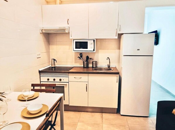 Una cocina compacta equipada con microondas, estufa, lavaplatos y refrigerador.