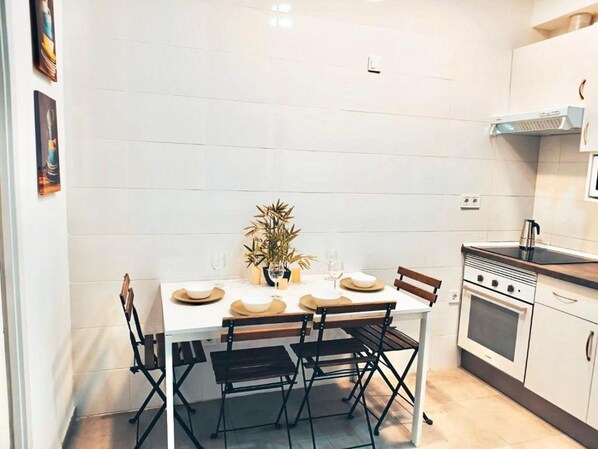 A compact kitchen with a dining table, chairs, a stove, and a microwave.