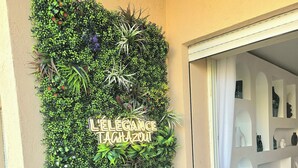 Un jardin vertical agrémenté d’une enseigne portant l’inscription « ÉLÉGANCE TAHOZOUIT », le tout sur un mur de couleur beige.