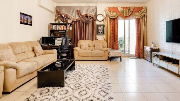 A living room with two sofas, a coffee table, a bookshelf, a television, and a large window with curtains.