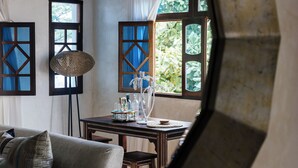 Habitación con ventanal redondo, ventilador de techo, una mesa con cristalería y vistas a zonas verdes.