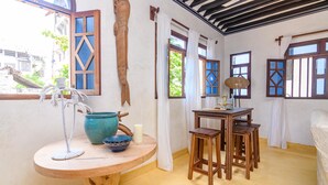 Una habitaci ón con una mesa de madera, un lavabo con lavamanos azul y una ventana con cortinas.