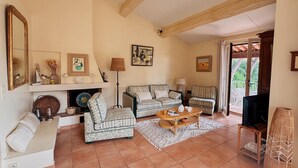 Un salon chaleureux avec une cheminée, deux canapés à motifs, une table basse et un téléviseur.