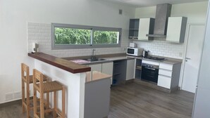 A modern kitchen with a wooden island, white cabinets, a microwave, and a stove. - House in Meadows of San Lorenzo - San Lorenzo Chico / Salta (Salta)