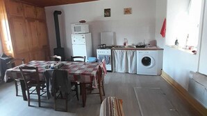 Una cocina rústica y acogedora con techo de madera, un comedor con mesa y sillas, lavadora y estufa.