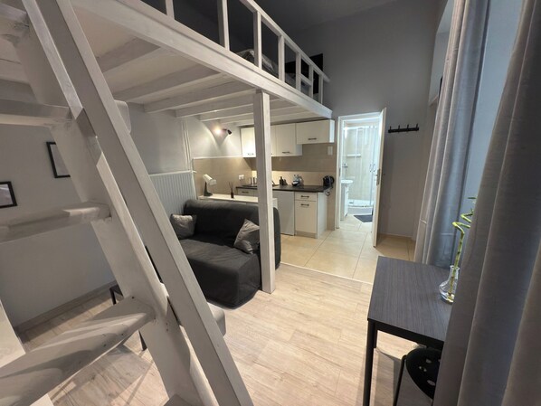 A modern loft-style apartment with a loft bed, a kitchen area, and a dining space.