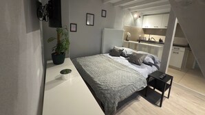 Ein modernes Schlafzimmer mit Bett, Nachttisch und einer Topfpflanze.