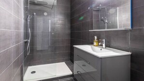 A modern bathroom with a glass shower enclosure, a white sink, and a mirror above it. - LARGE APARTMENT, 5 min from Saint-Charles train station (Marseille)
