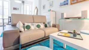 A modern living room with a beige sofa, a glass coffee table, and a small cactus plant. - LARGE APARTMENT, 5 min from Saint-Charles train station (Marseille)