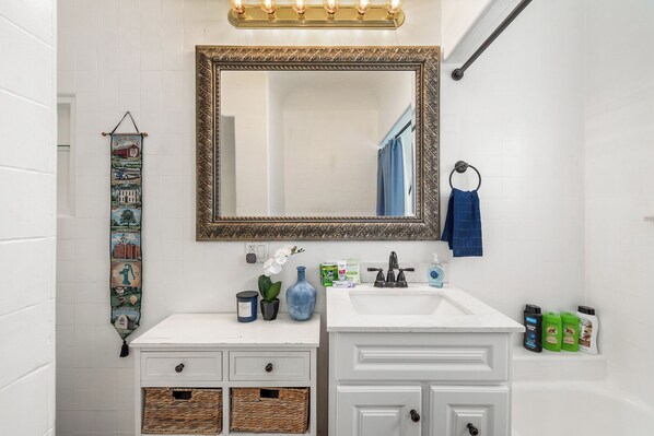Une salle de bain avec un grand miroir, un meuble-lavabo blanc et un porte-serviettes.