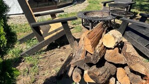 A geodesic dome tent with a fire pit and wooden furniture.
