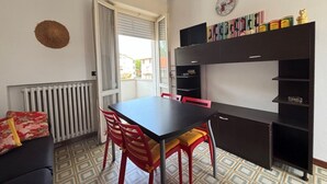 A room with a dining table, red chairs, a black cabinet, and a radiator.