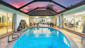Ein Swimmingpool mit Glasveranda, Steintreppe und Gartenmöbeln.