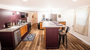 Une cuisine moderne avec des meubles en bois, des appareils en acier inoxydable et un îlot central doté de tabourets de bar.