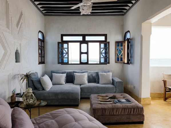 Una sala de estar con un sofá seccional, un reposapiés y una estatua decorativa de un mono.