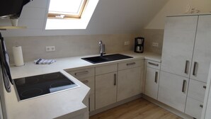 A modern kitchen with a skylight, a built-in stove, a sink, and cabinets.