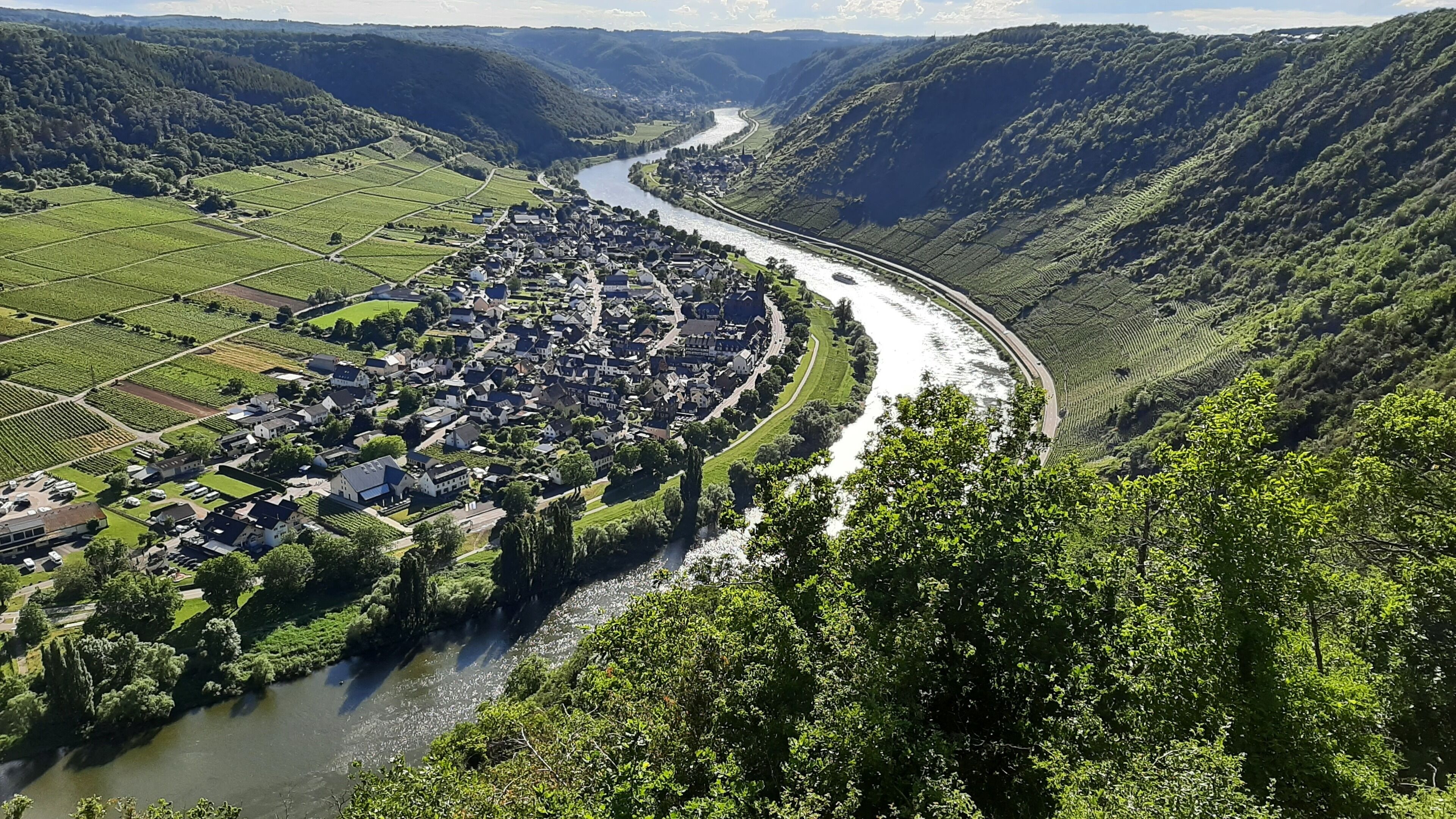 A river winding through a town surrounded by lush green hills.