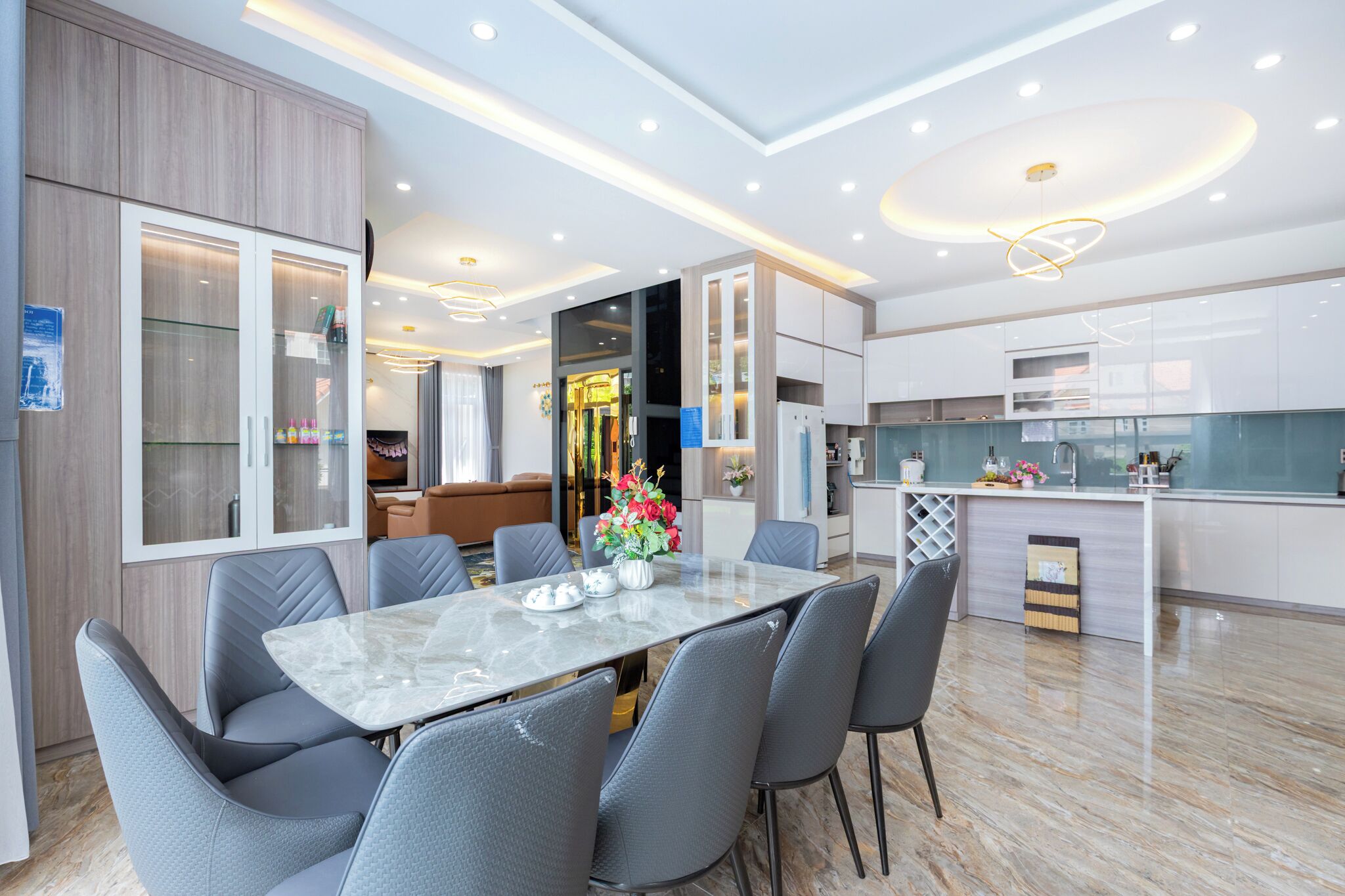 A modern kitchen with white cabinets, a marble countertop, and a built-in oven.