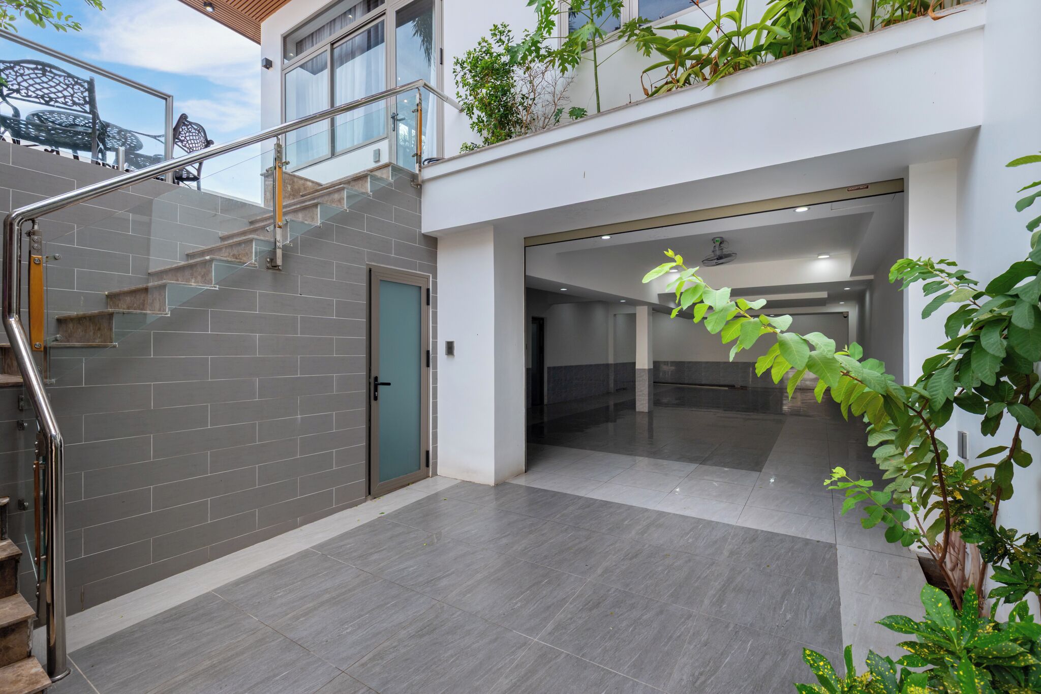 Um edifício moderno com escada, guarda-corpo de vidro e uma porta.
