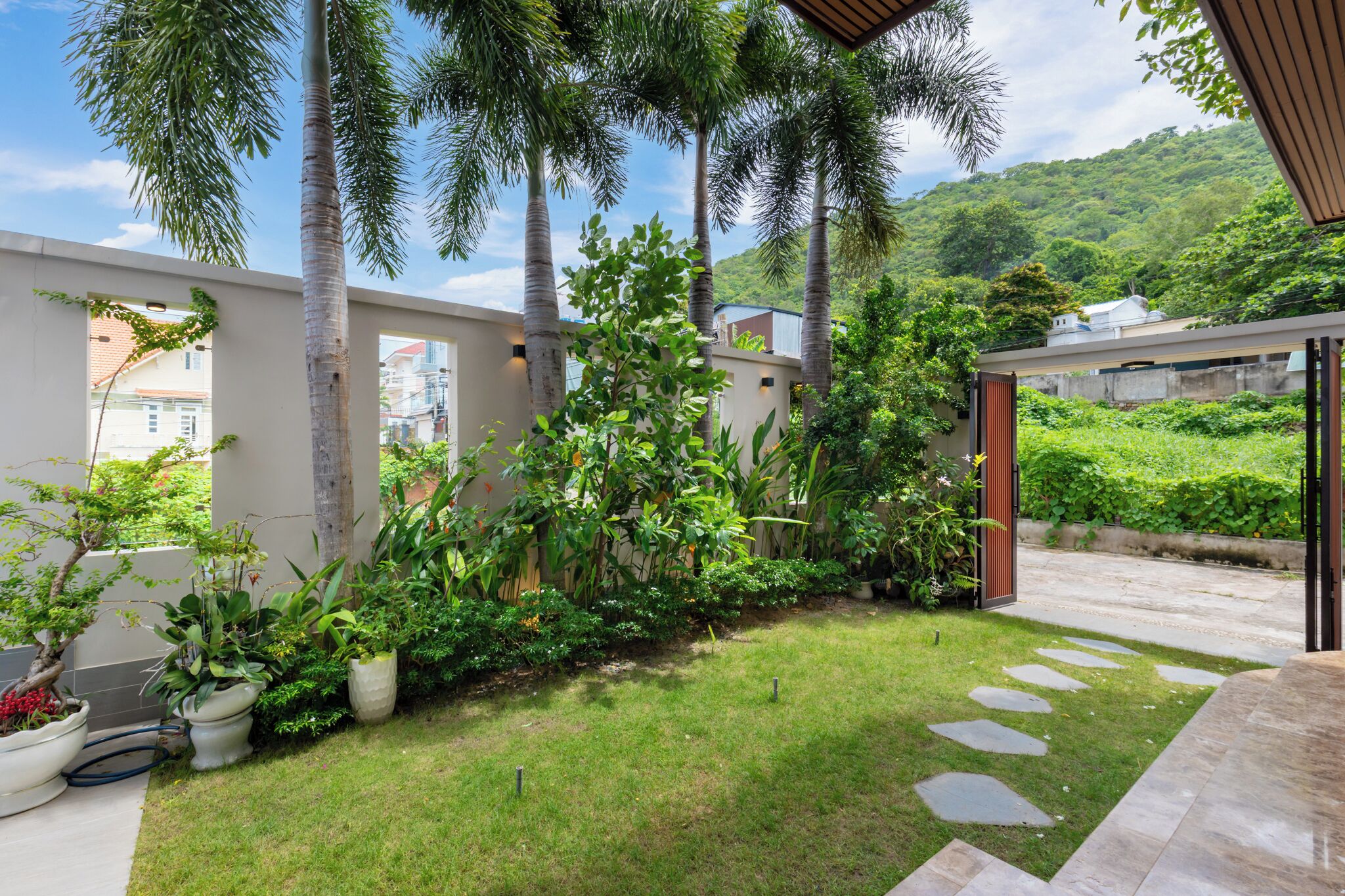 A well-maintained garden with a variety of plants and a stone pathway leading to a building.